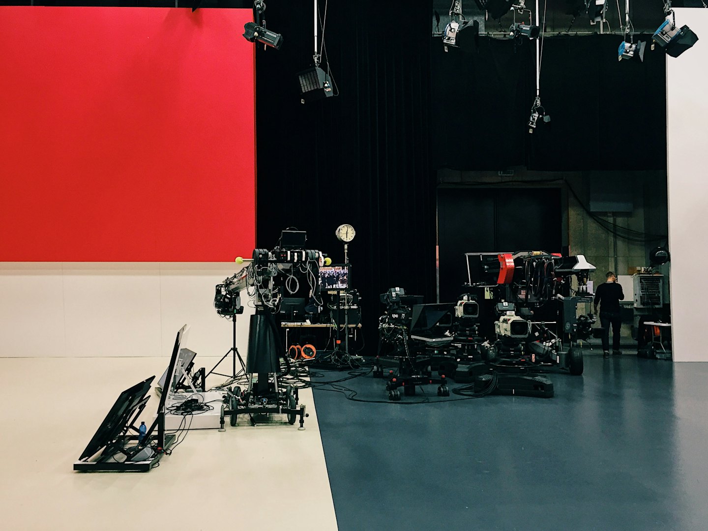 Televizní studio s vysílacími kamerami a produkčním vybavením.